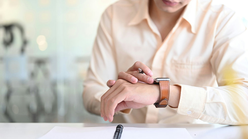 A man checking his watch, waiting for the best time to refinance his house.