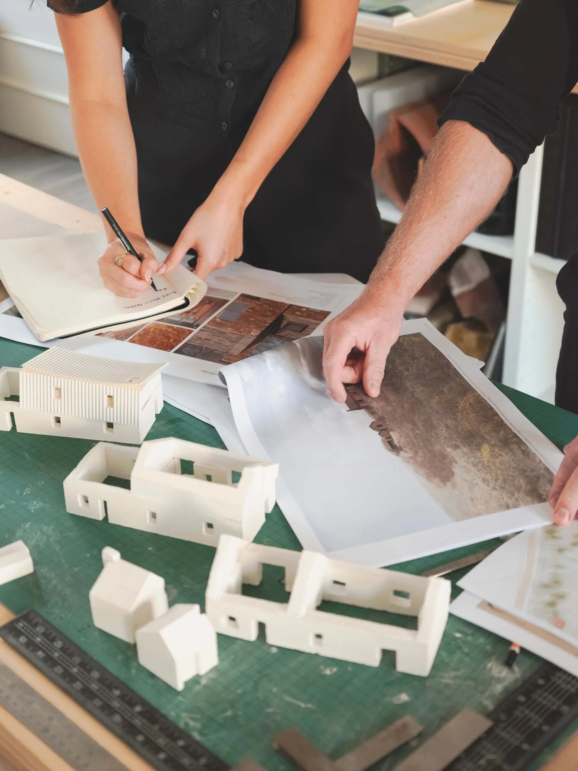 Zoomed in, detail focused photo, showing Ed and Angel going through a printed document for a house project.