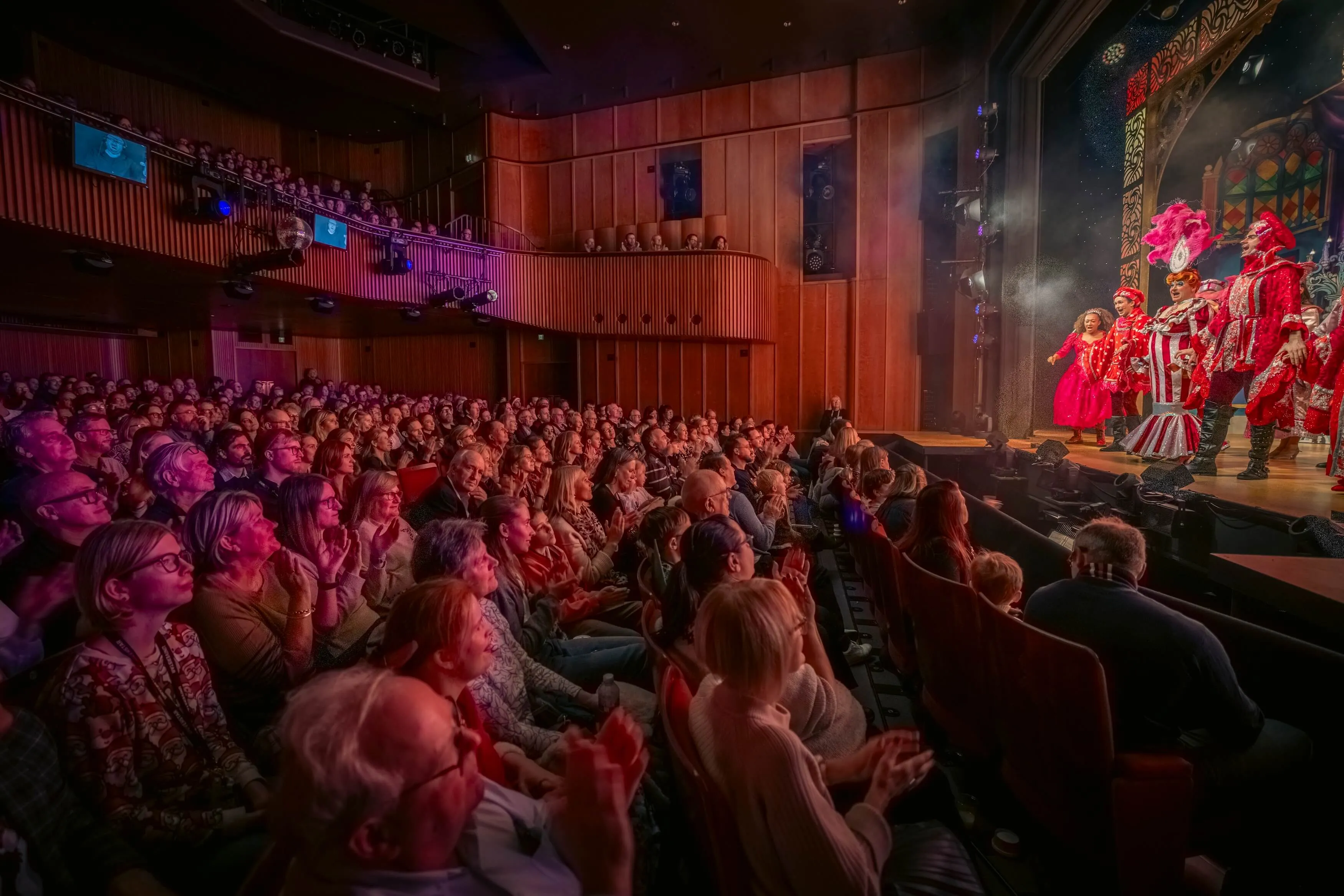 Shot of the theatre during a performance, showing in wide angle the stage and the audience.