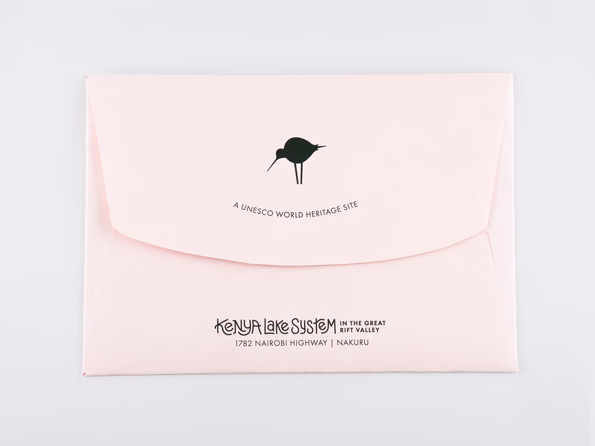 Light pink envelope with black text and a bird logo, reading 'A UNESCO World Heritage Site' and 'Kenya Lake System in the Great Rift Valley, 1782 Nairobi Highway | Nakuru.'