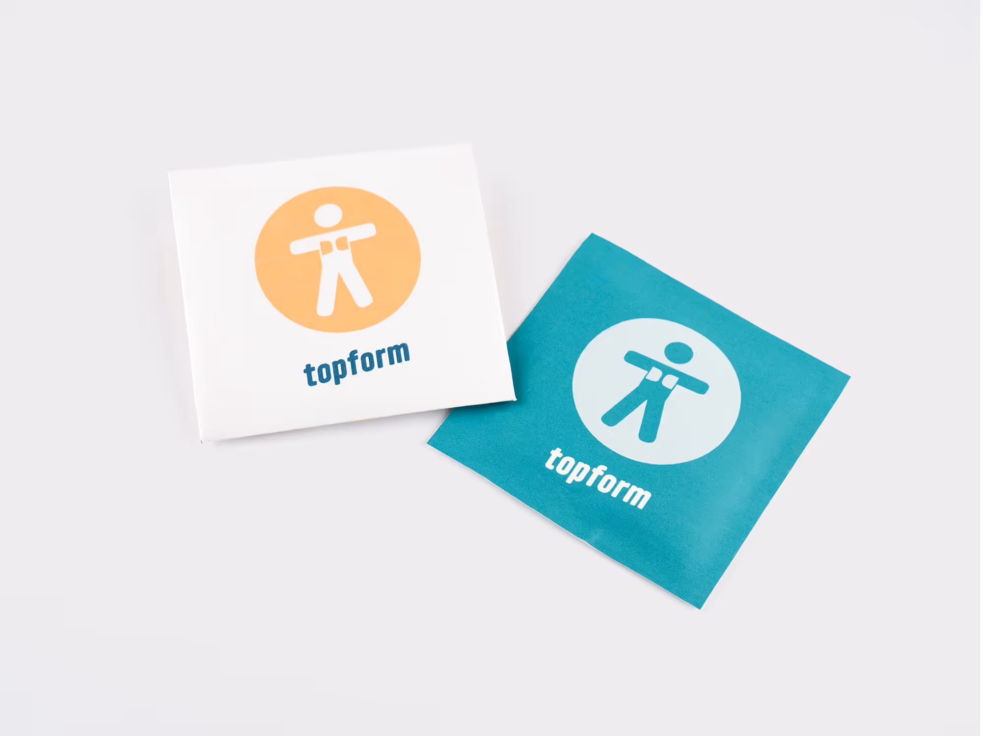 Two square packets with the topform logo, one white with an orange circle and the other teal with a light blue circle, placed on a white surface.