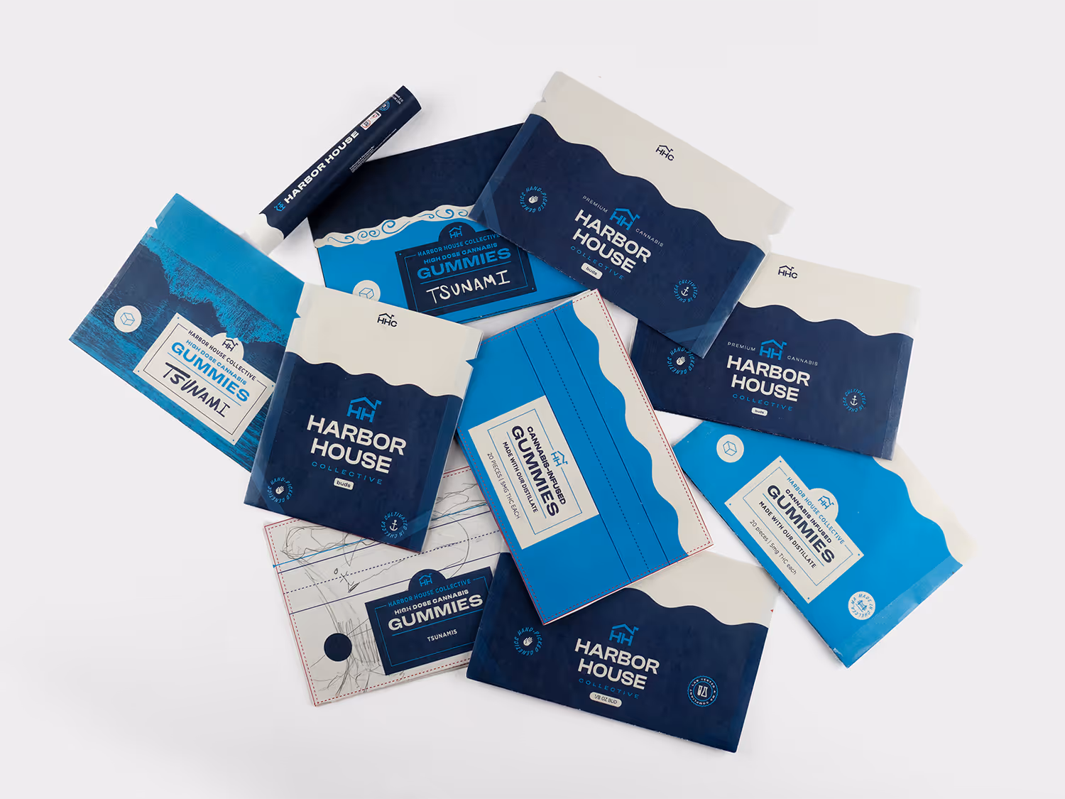 Flat lay of Harbor House Collective blue and white cannabis gummy packaging drafts printed on printer paper on a white background.
