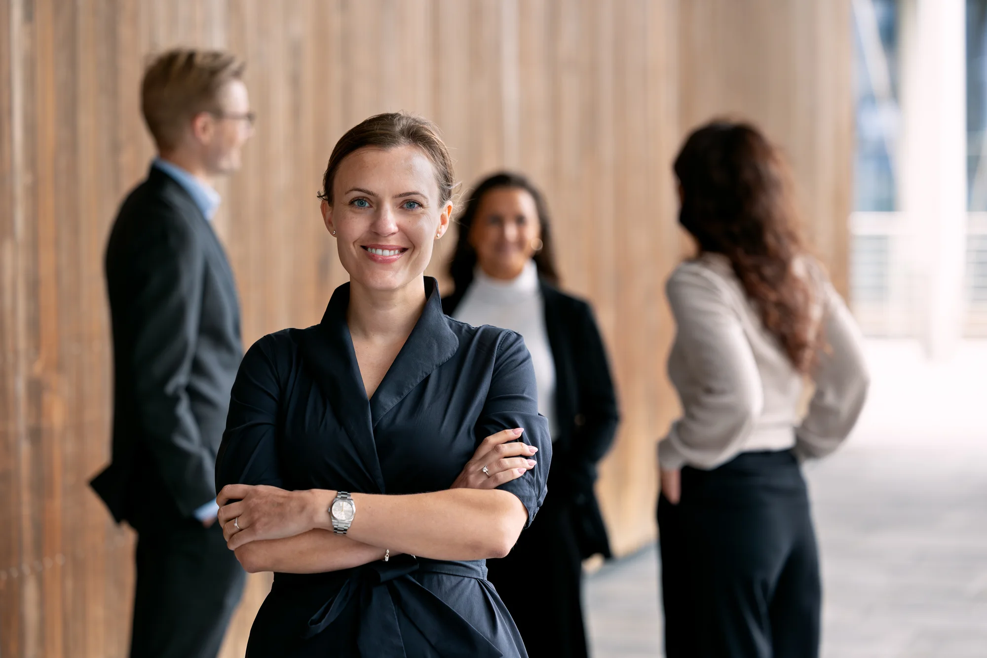 A business portrait showing a woman with colleagues in a modern office