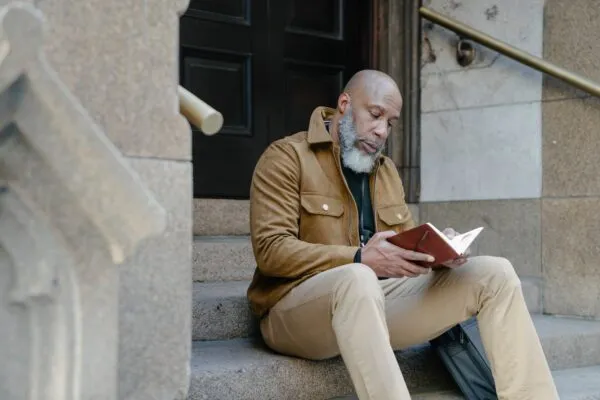 A man reading a contractor book on the stairs