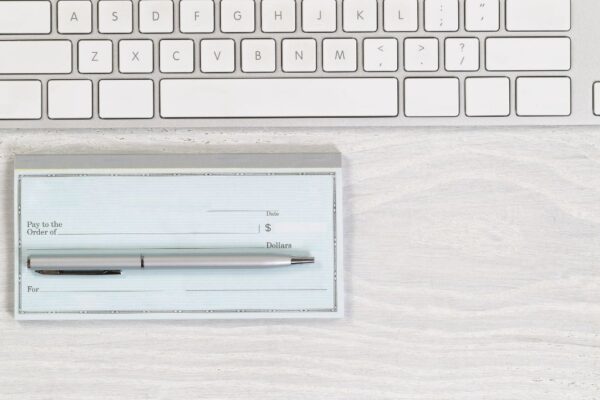 A checkbook next to a computer keyboard