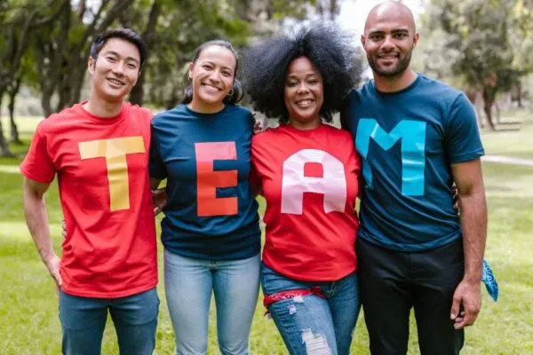 Four people wearing shirts that spell out team for team culture