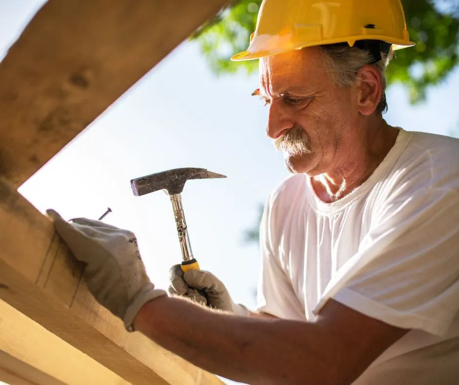 elderly roofer hammering a nail