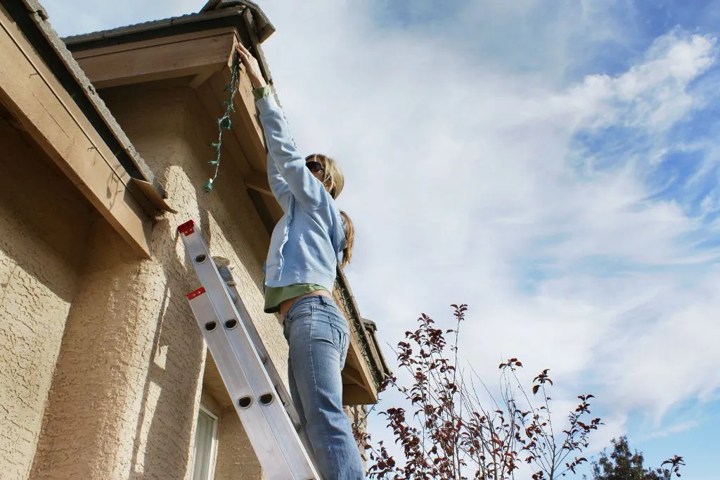 A roofer getting extra income by hanging up exterior holiday lights