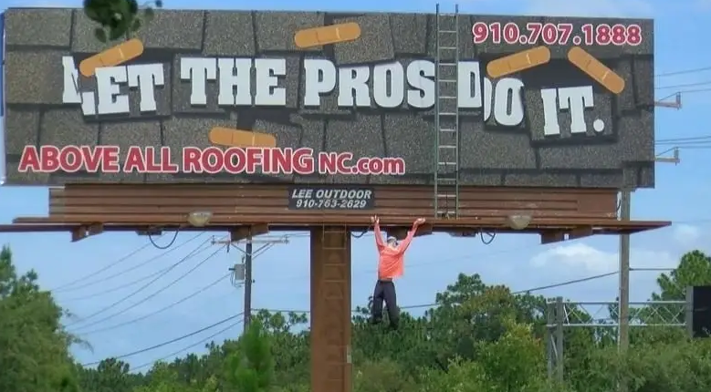 Let the Pros Do It roofing billboard with a mannequin dangling off the edge