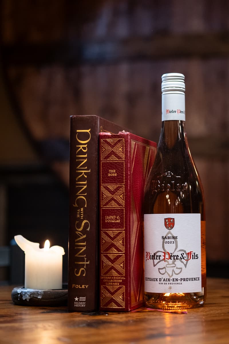 A bottle of wine next to books and a lit candle