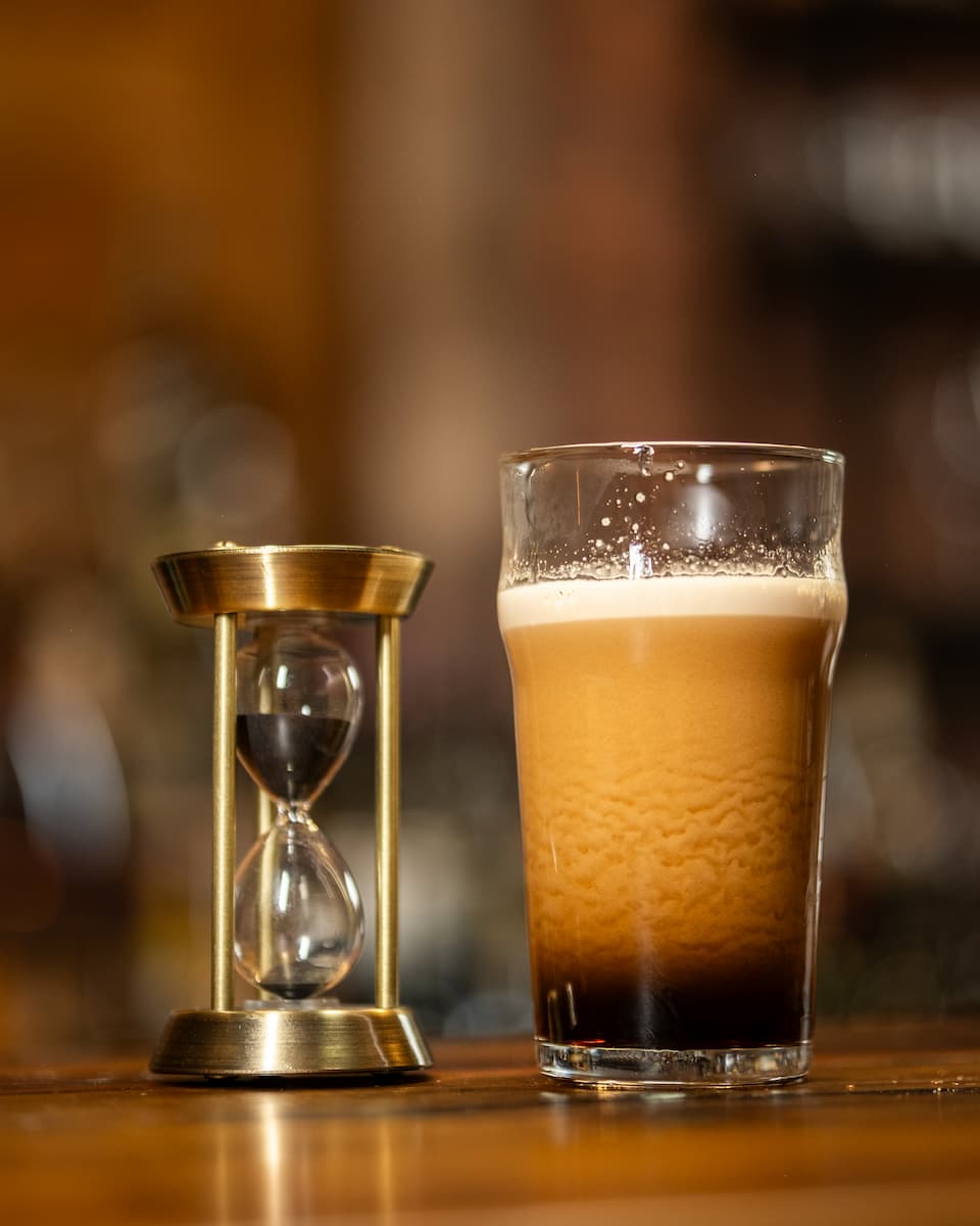 A Black and Tan sitting next to an hourglass