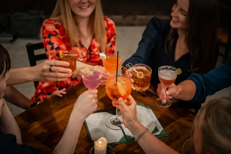 Guests toasting cocktails around a table at Paradiso