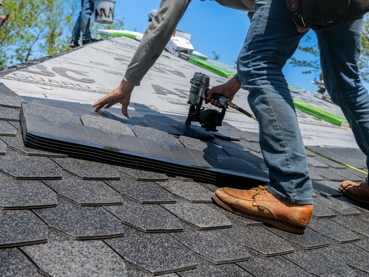 Roofer installing shingles on a new roof