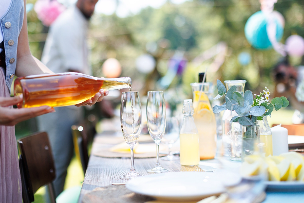 Close-up of wine being poured at a summer garden party table with glasses and lemonade, capturing the relaxed elegance of a Scottsdale cocktail gathering.