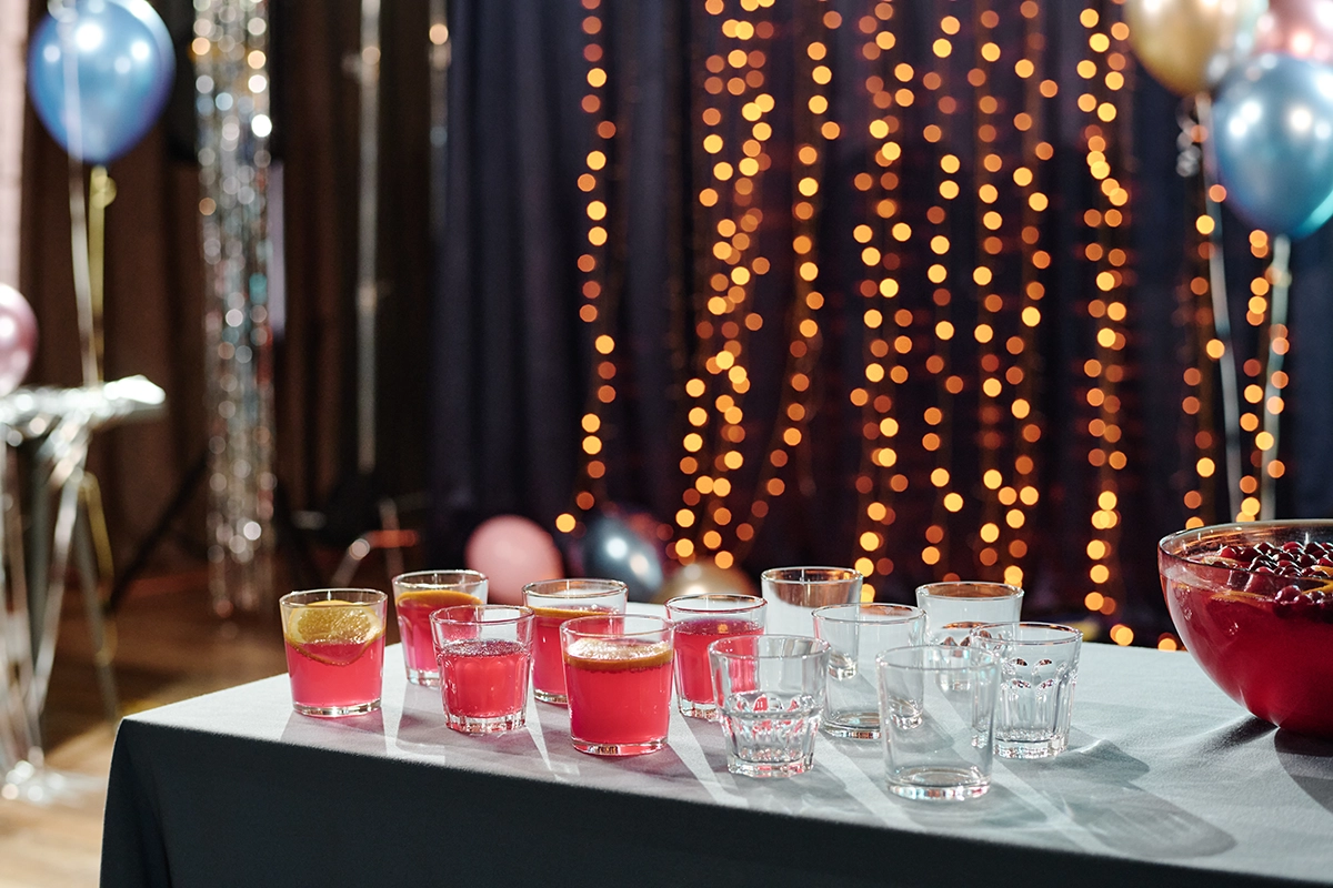 Table with pink cocktails garnished with lemon slices and surrounded by glassware, creating a festive and elegant Scottsdale party atmosphere.