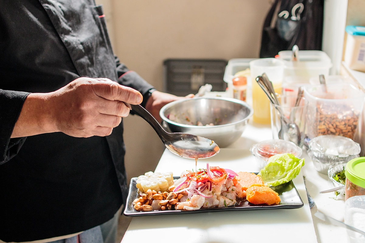 Chef performing tableside food presentation with sauce finishing at a luxury catered event