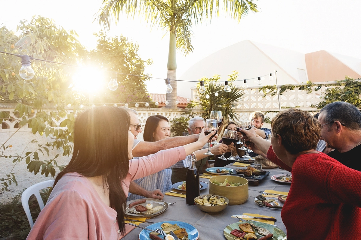 Guests of all ages enjoying a memorable luxury Fourth of July celebration with private chef catering in a sunny Scottsdale backyard, raising glasses around a table filled with shared dishes and festive outdoor dining