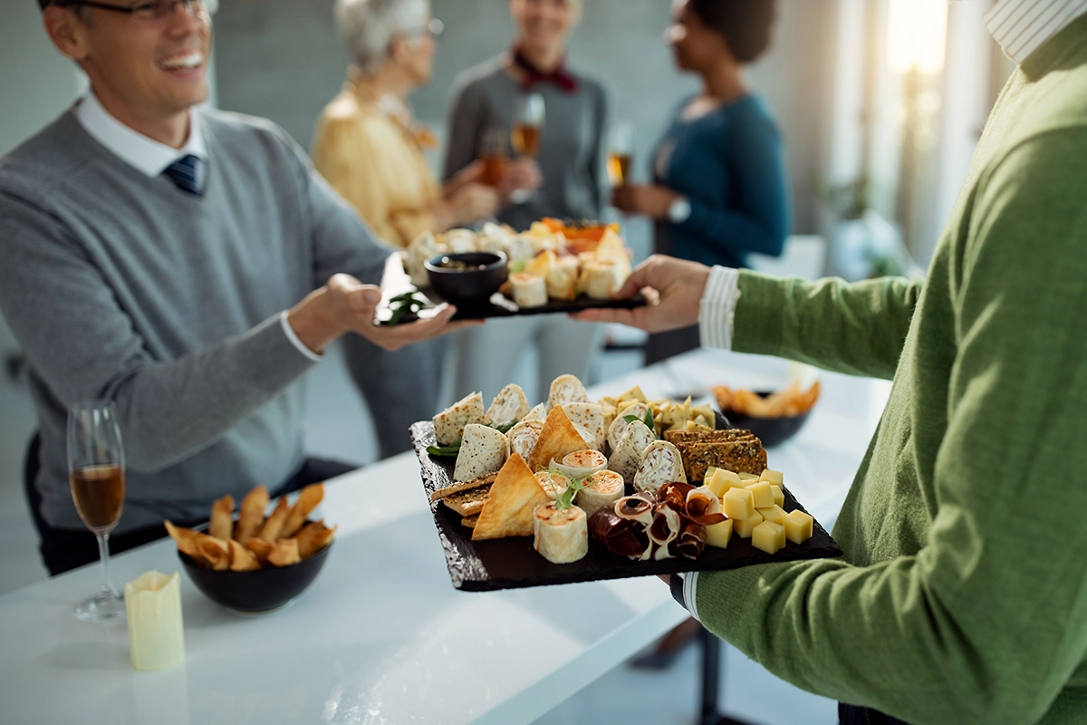 Guests gathered indoors with passed hors d'oeuvres at a Scottsdale dinner party, sharing appetizers, drinks, and conversation in a bright, elegant space.