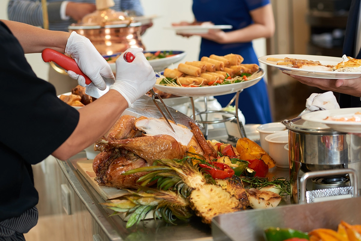 Chef carving roast turkey to order at a Thanksgiving carving station for guests.