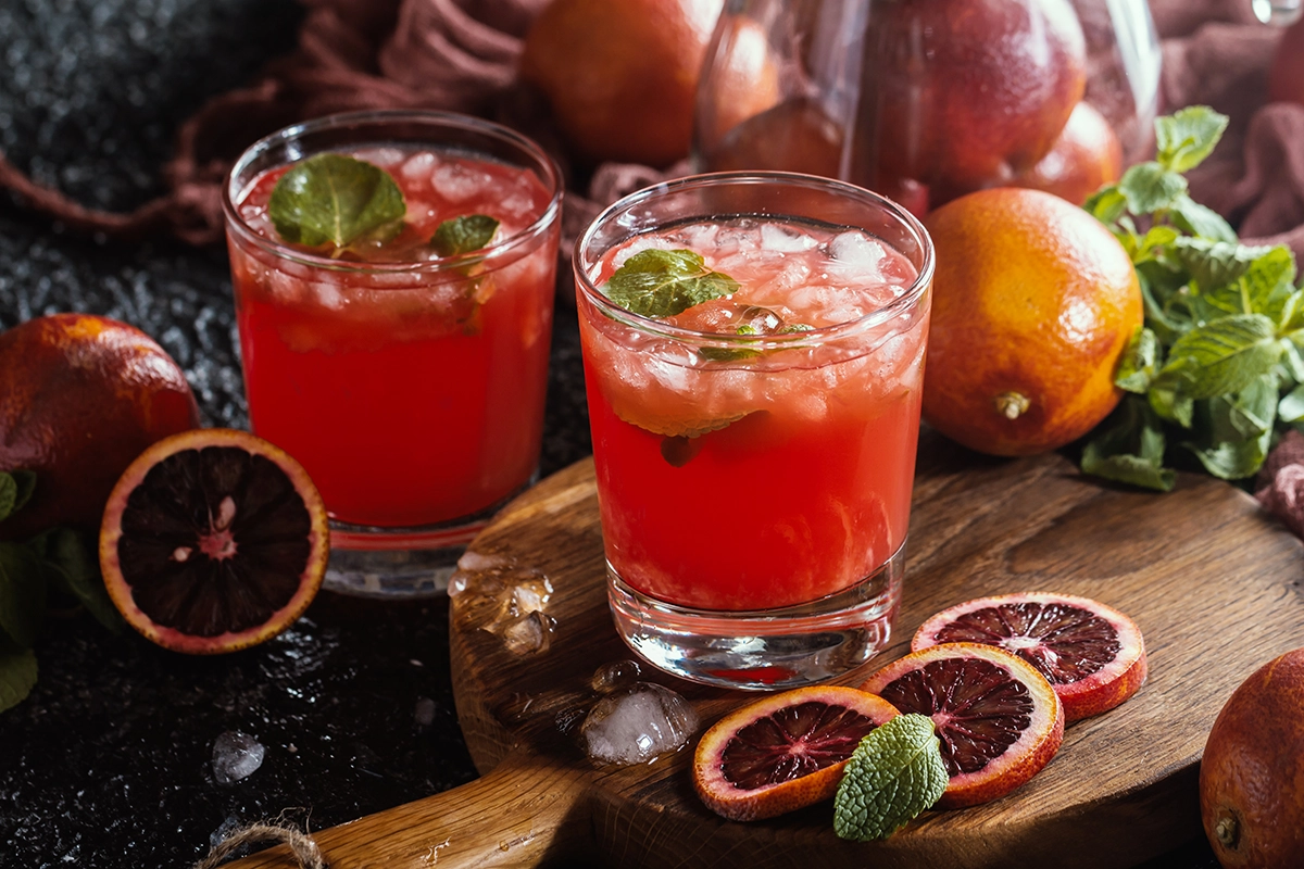 Blood orange holiday cocktail and a matching zero-proof mocktail served side by side in identical glasses