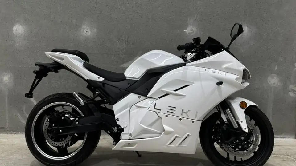 A gloss-white Leki electric motorbike in side profile against a concrete wall