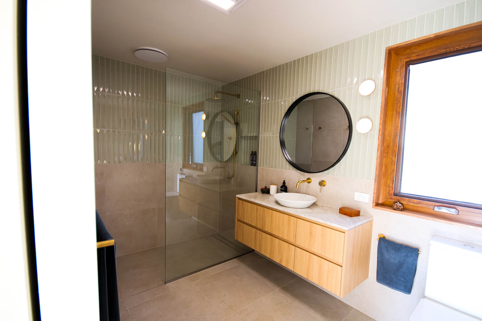 bathroom renovation hobart for birchs bay couple showing brown timber vanity, black mirror and green tiles