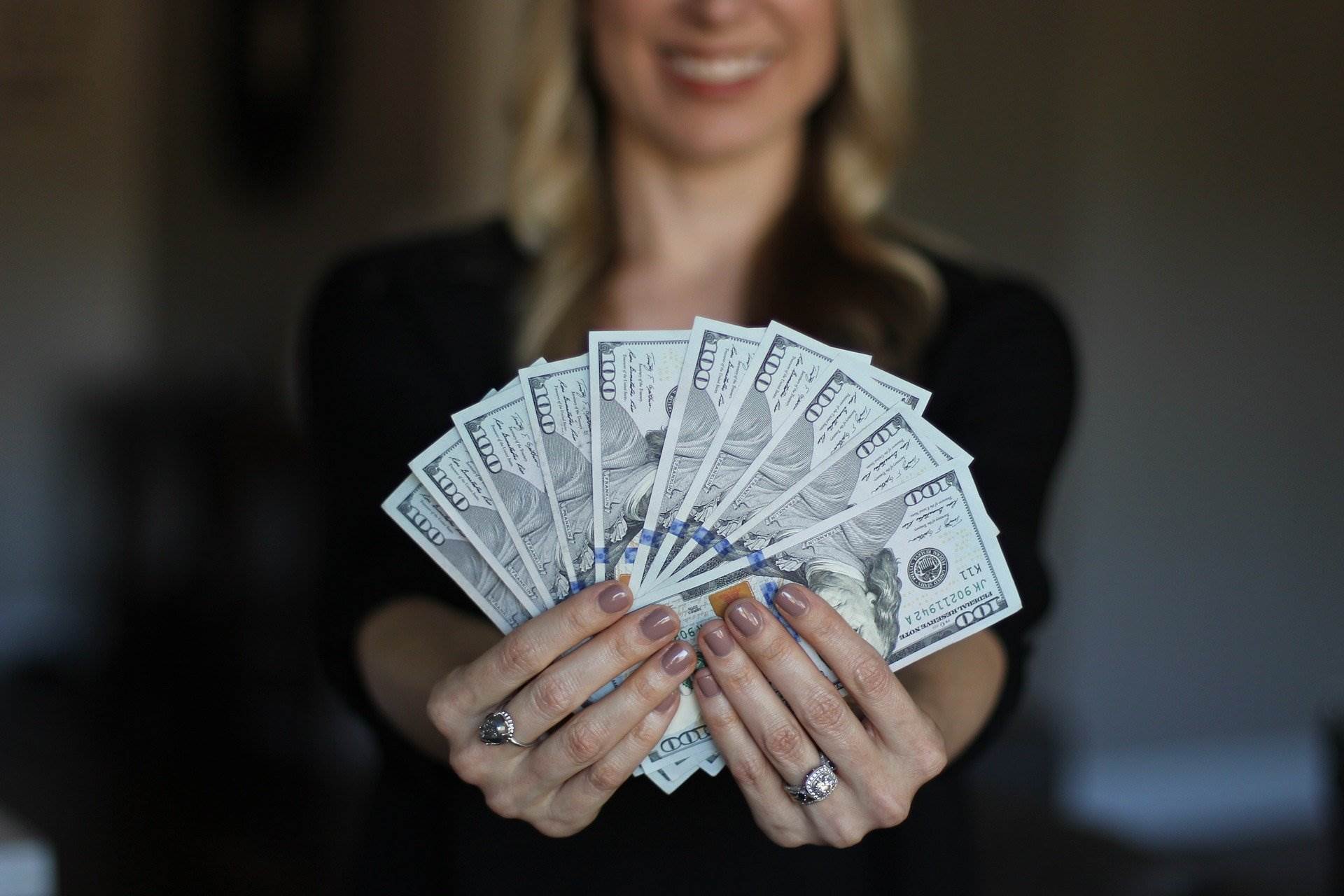 woman holding money - How to Day Trade for a Living