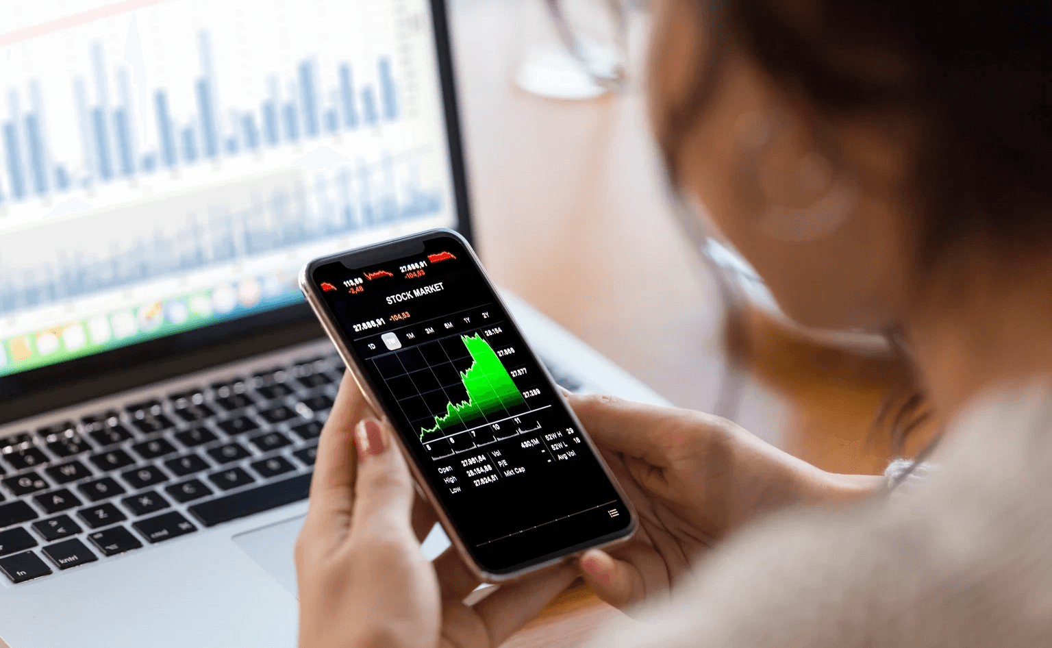 Woman tracking stock market on phone - How Much Money Do You Need To Start Trading Options