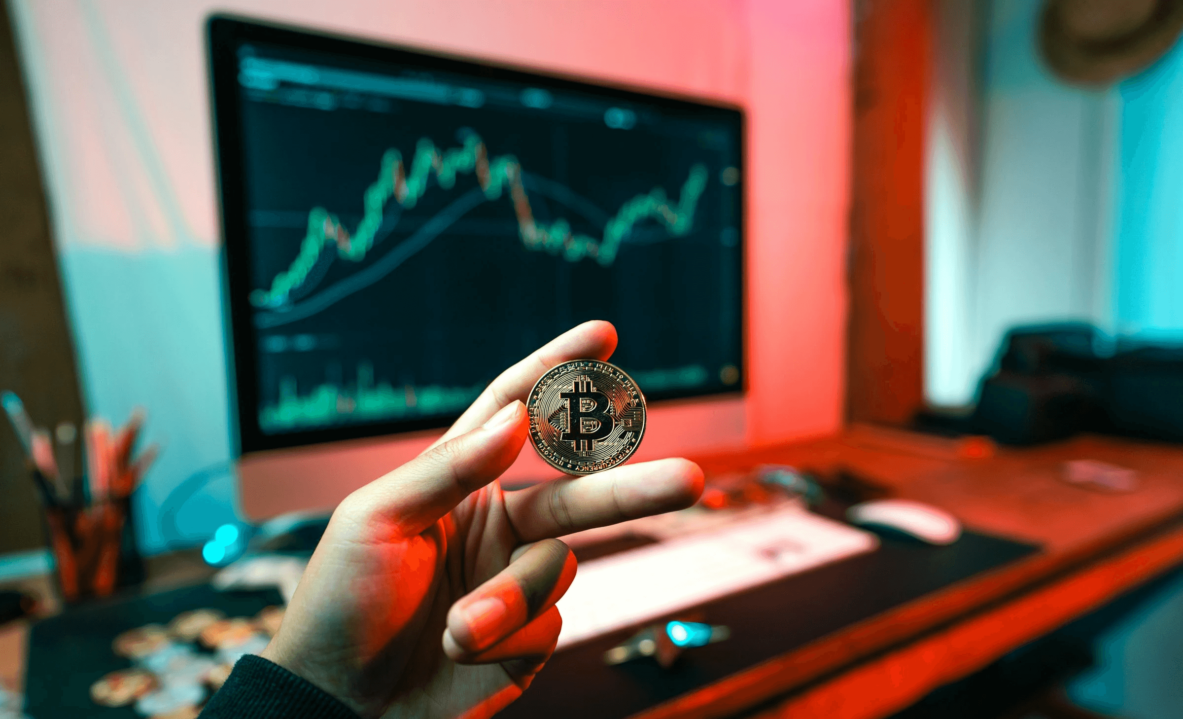 Person holding Bitcoin before financial chart - What Is The Most Profitable Trading Strategy