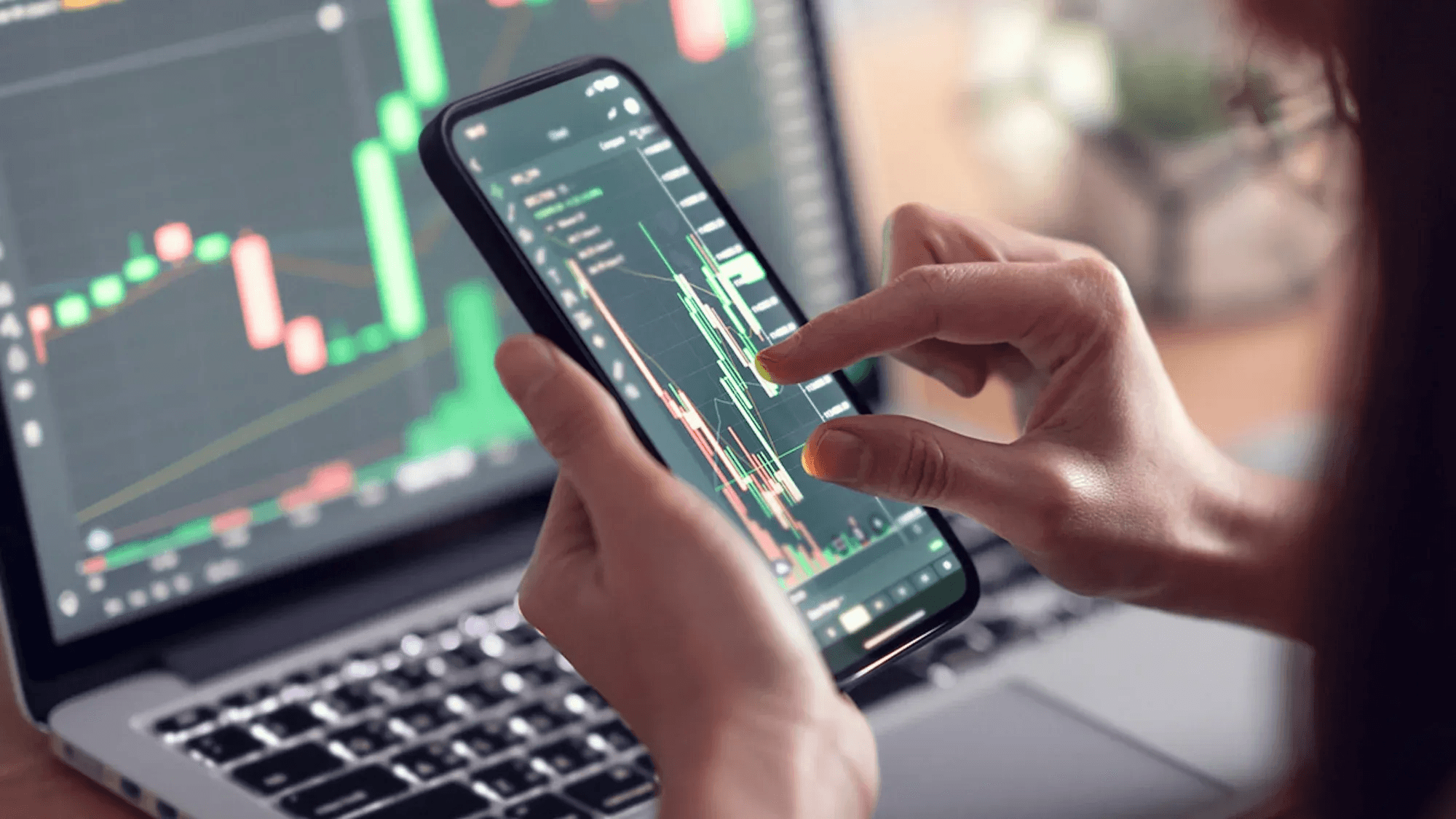 Person checking stock market on phone - How to Learn Stock Trading for Beginners