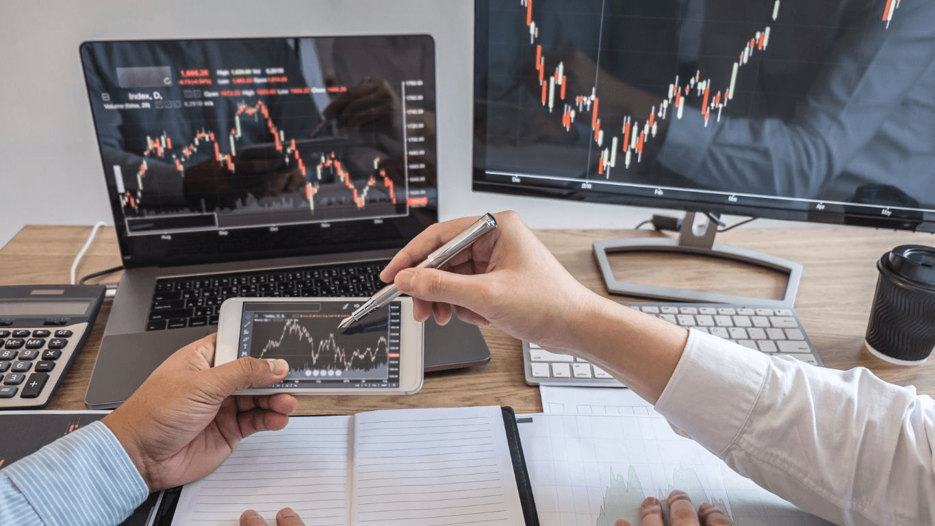  Traders discussing market data on screens - Backtesting Trading Strategies