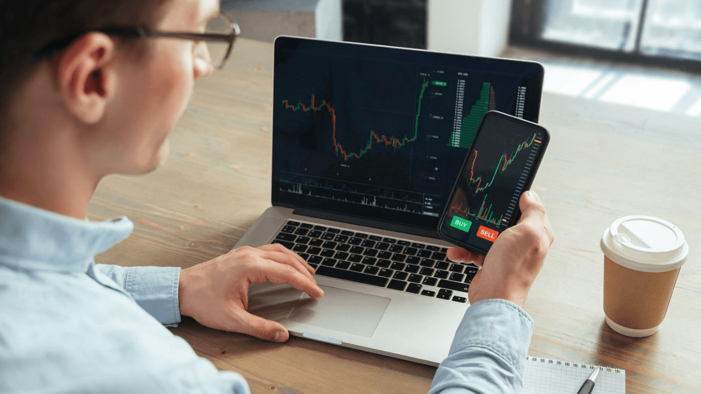 Man trading stocks on multiple devices -  What is Arbitrage Trading