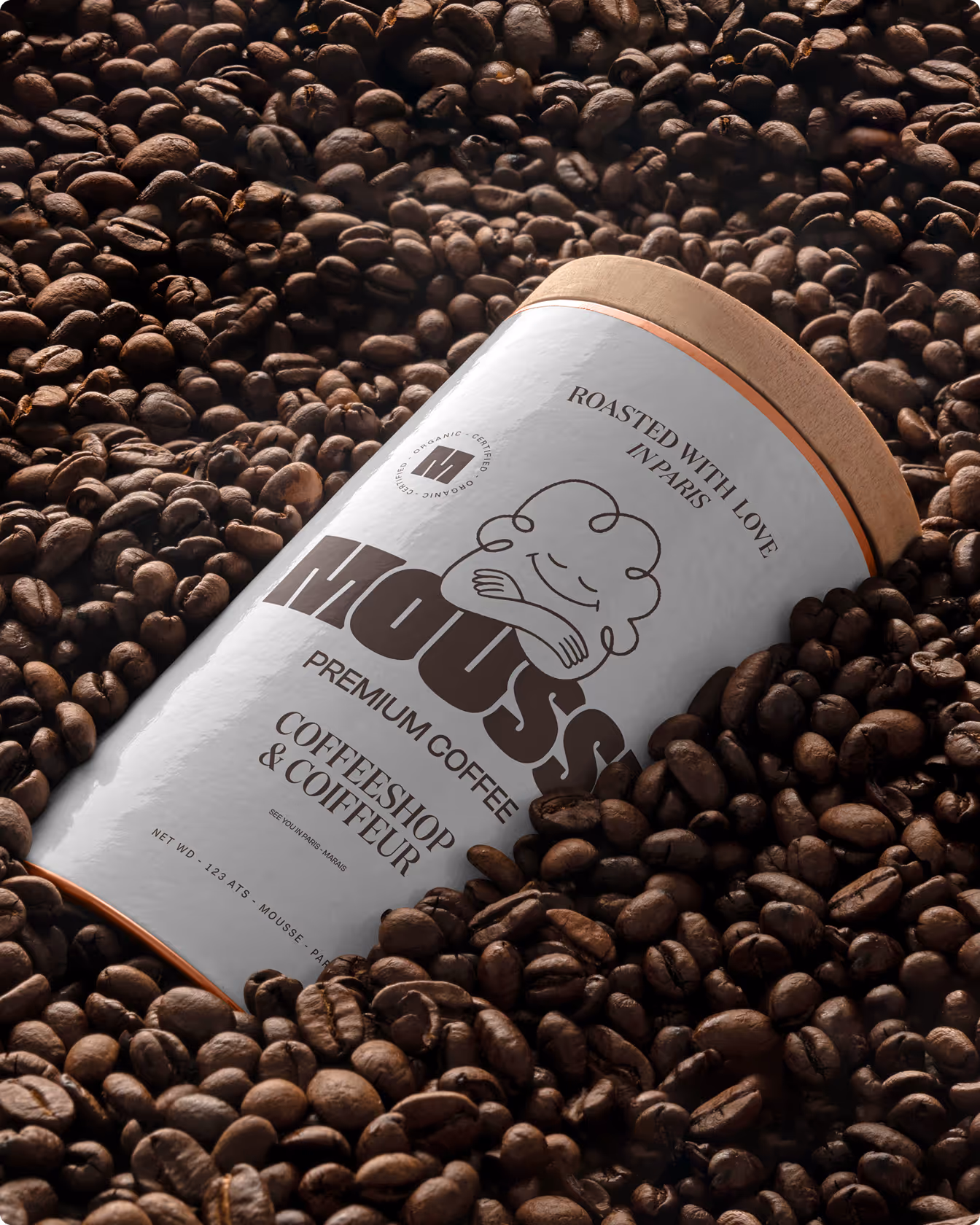 Une boîte de café Mousse blanche avec couvercle en bois est posée sur un lit de grains de café brun.