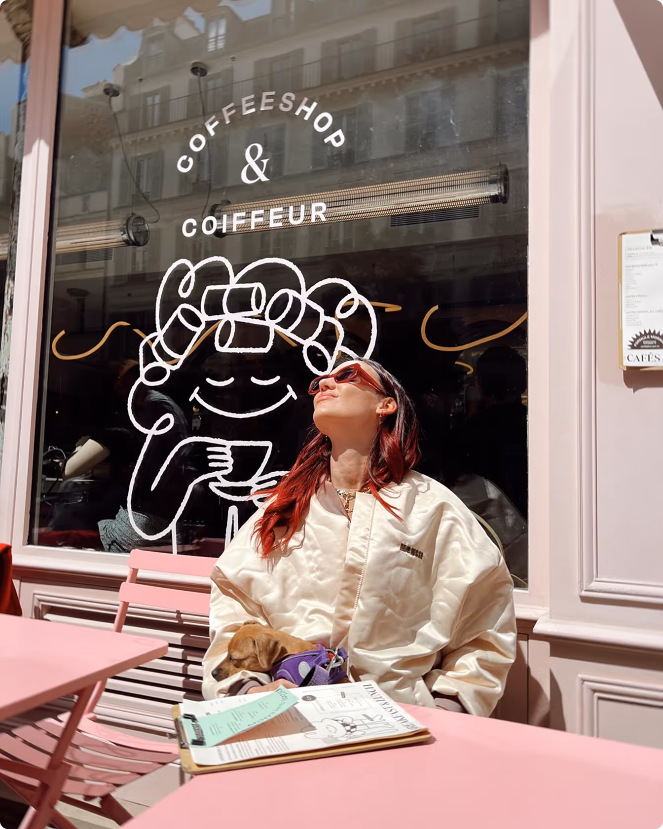 Femme assise en terrasse devant la vitrine du coffeeshop Mousse à Paris, profitant du soleil avec un chien sur les genoux