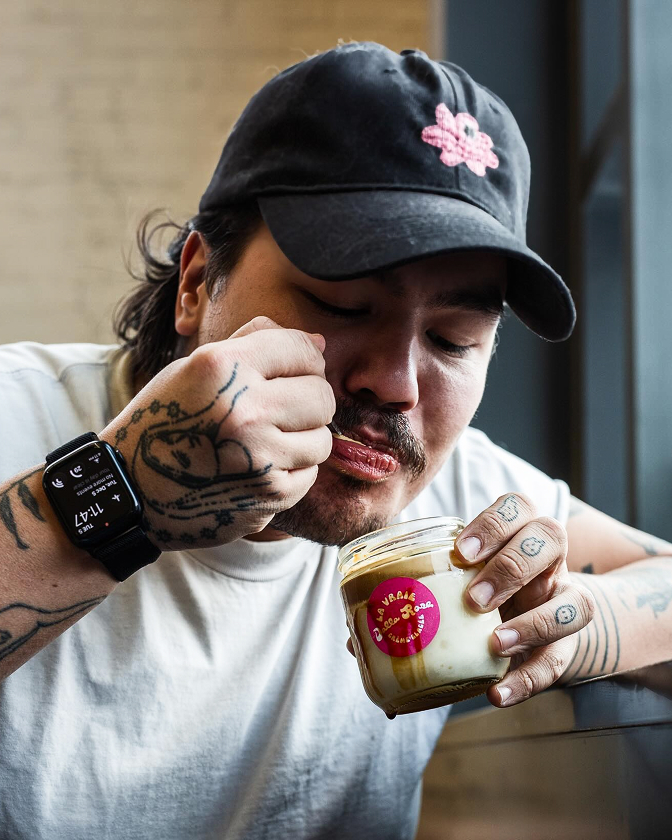 Homme portant une casquette noire SAVSAV dégustant un dessert en pot.