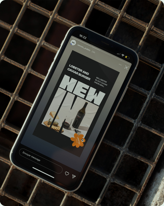 Un smartphone présente une campagne SavSav en noir et blanc avec le texte « NEW INK » et une touche d’orange.