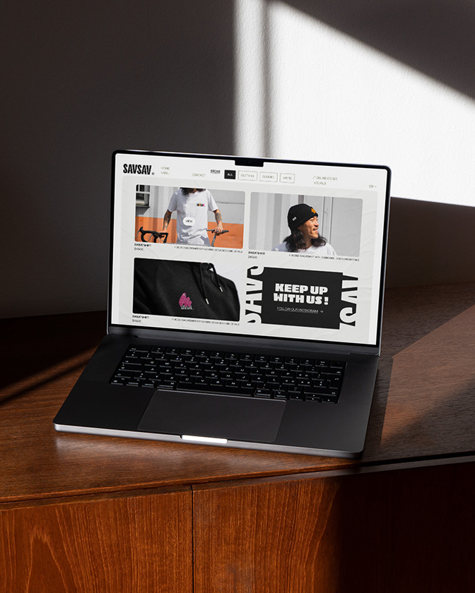 Un ordinateur portable ouvert montre le site web SavSav avec des visuels modernes en noir et blanc.