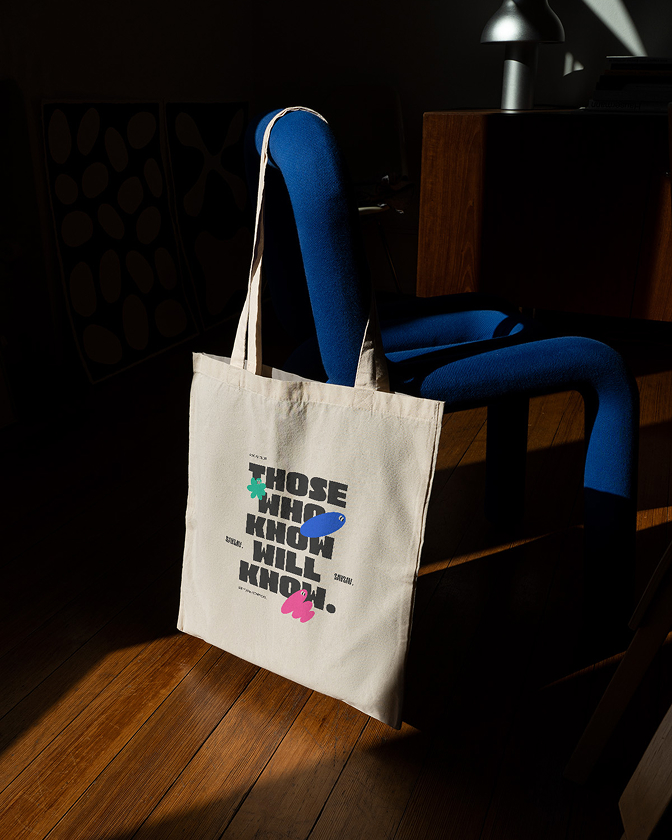 Un tote bag en coton SavSav affiche le slogan « Those who know will know » en lettres colorées.
