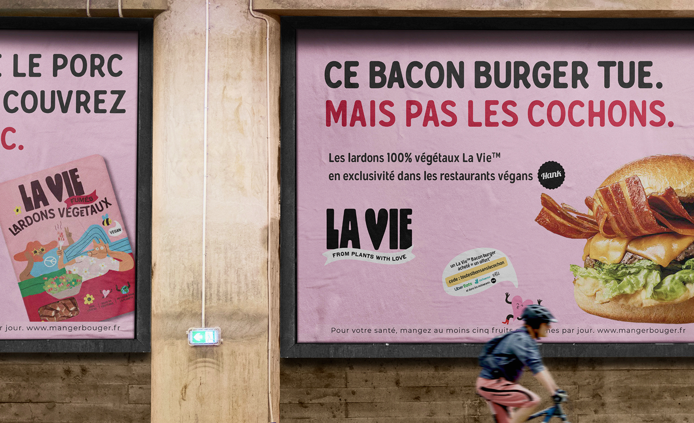 Affiches publicitaires La Vie avec slogans et visuel de burger végétal sur mur urbain.