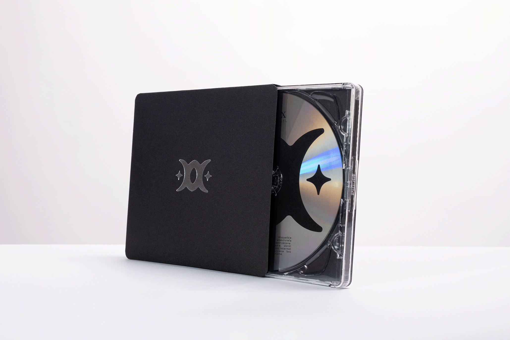 cd packaging with a silver logo on a cover with jewel case sticking out of it