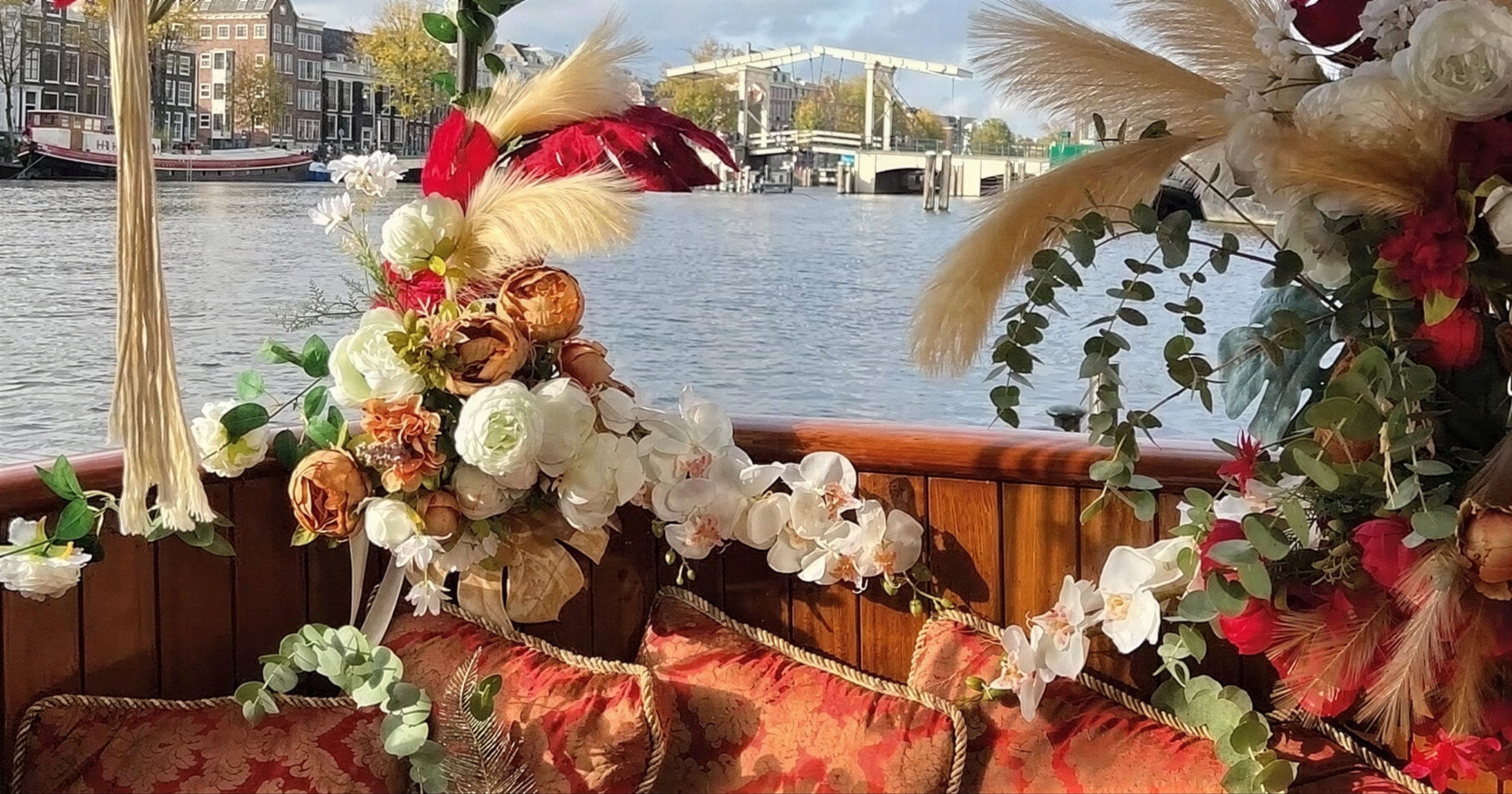 Kussens en bloemen aan boord van Valentijn met uitzicht op de Magere Brug
