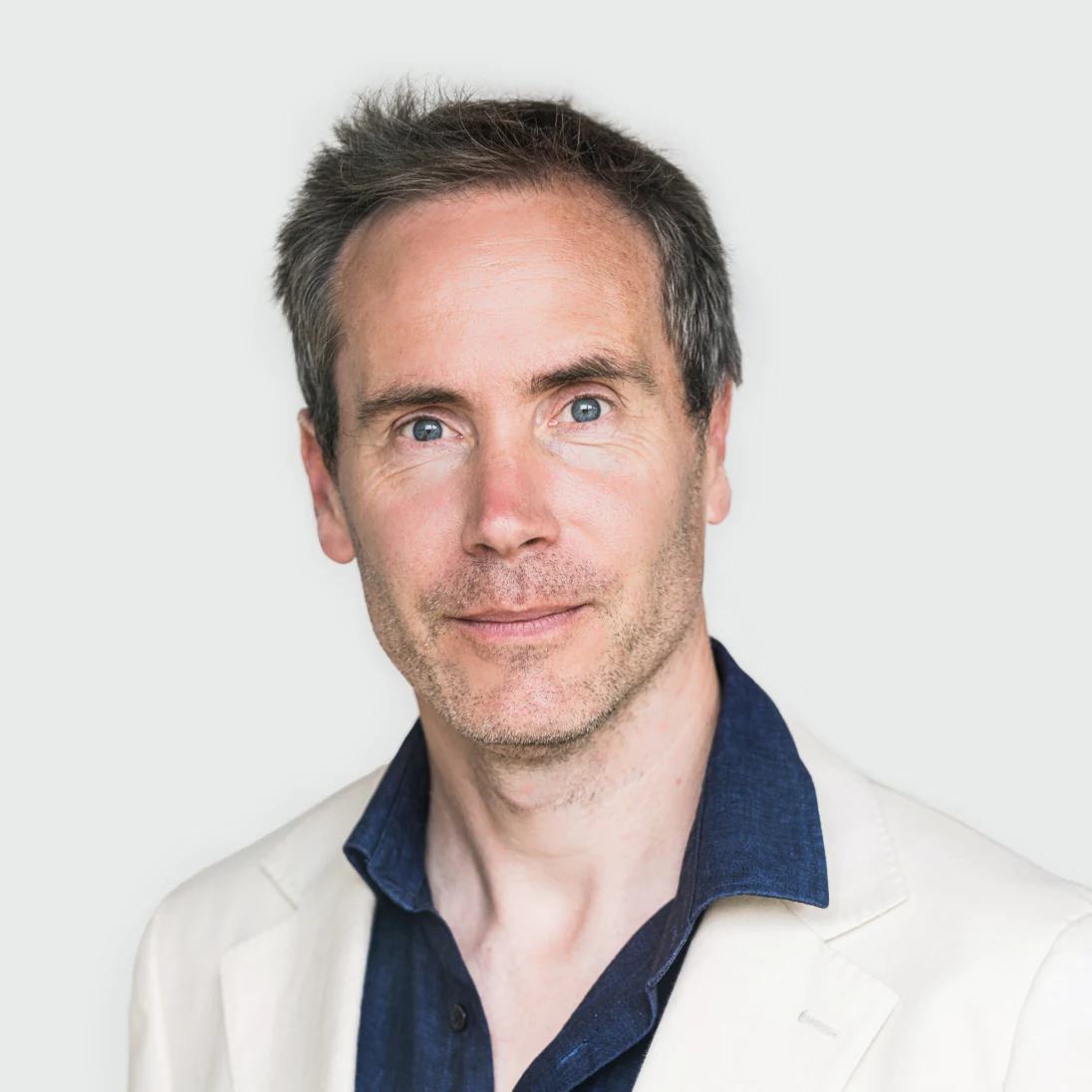 Photo of Dr. Vincent Plagnol, Chief Scientific Officer of Genomics Ltd, in a white jacket and dark shirt, looking forward.