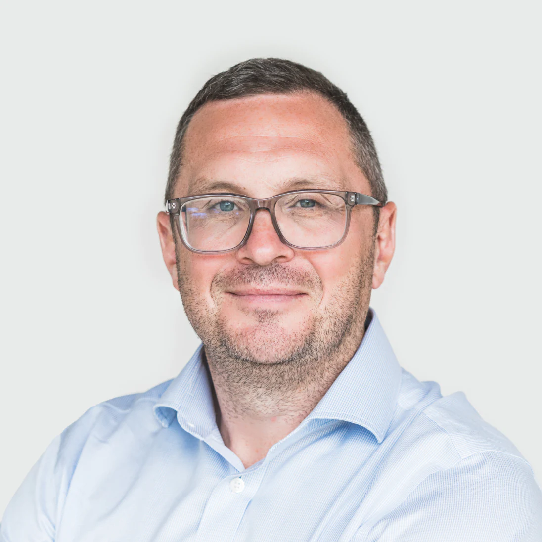 Photo of Dr. Seamus Harrison, Chief Medical Officer of Genomics Ltd, wearing glasses and a light shirt, smiling slightly.