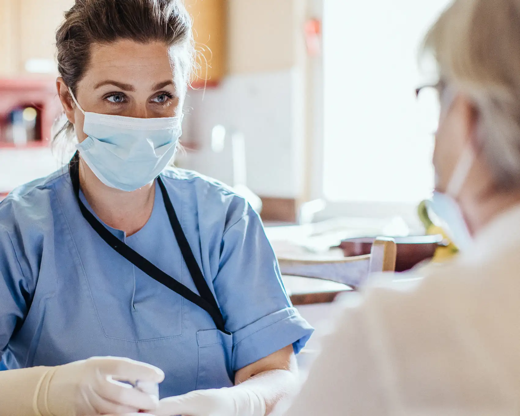 Clinician consulting with a patient in a medical exam room, highlighting Genomics’ efforts to identify high-risk individuals early through genetic testing.