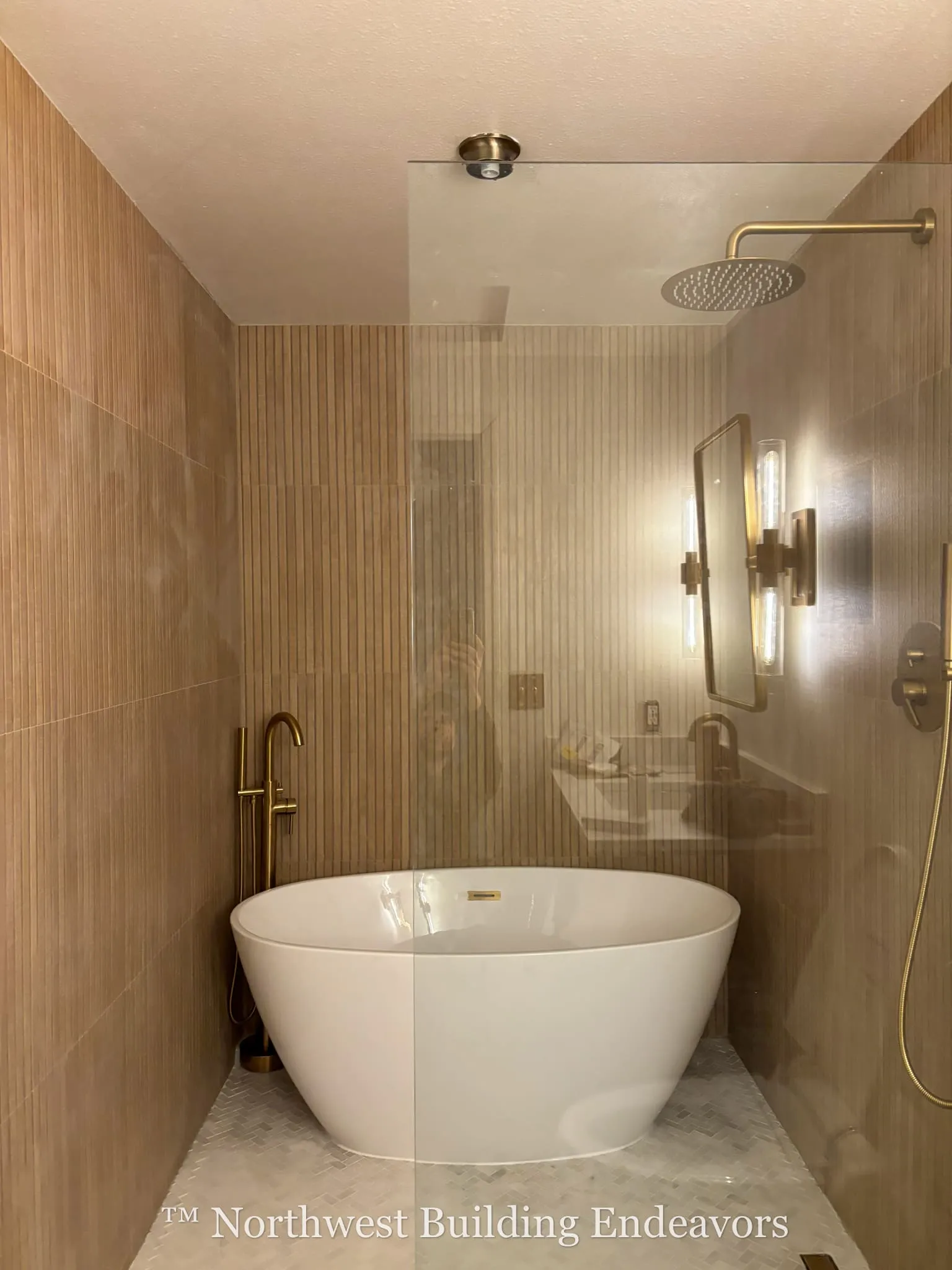 Modern bathroom with a white freestanding bathtub, brass fixtures, and wood-textured wall tiles.