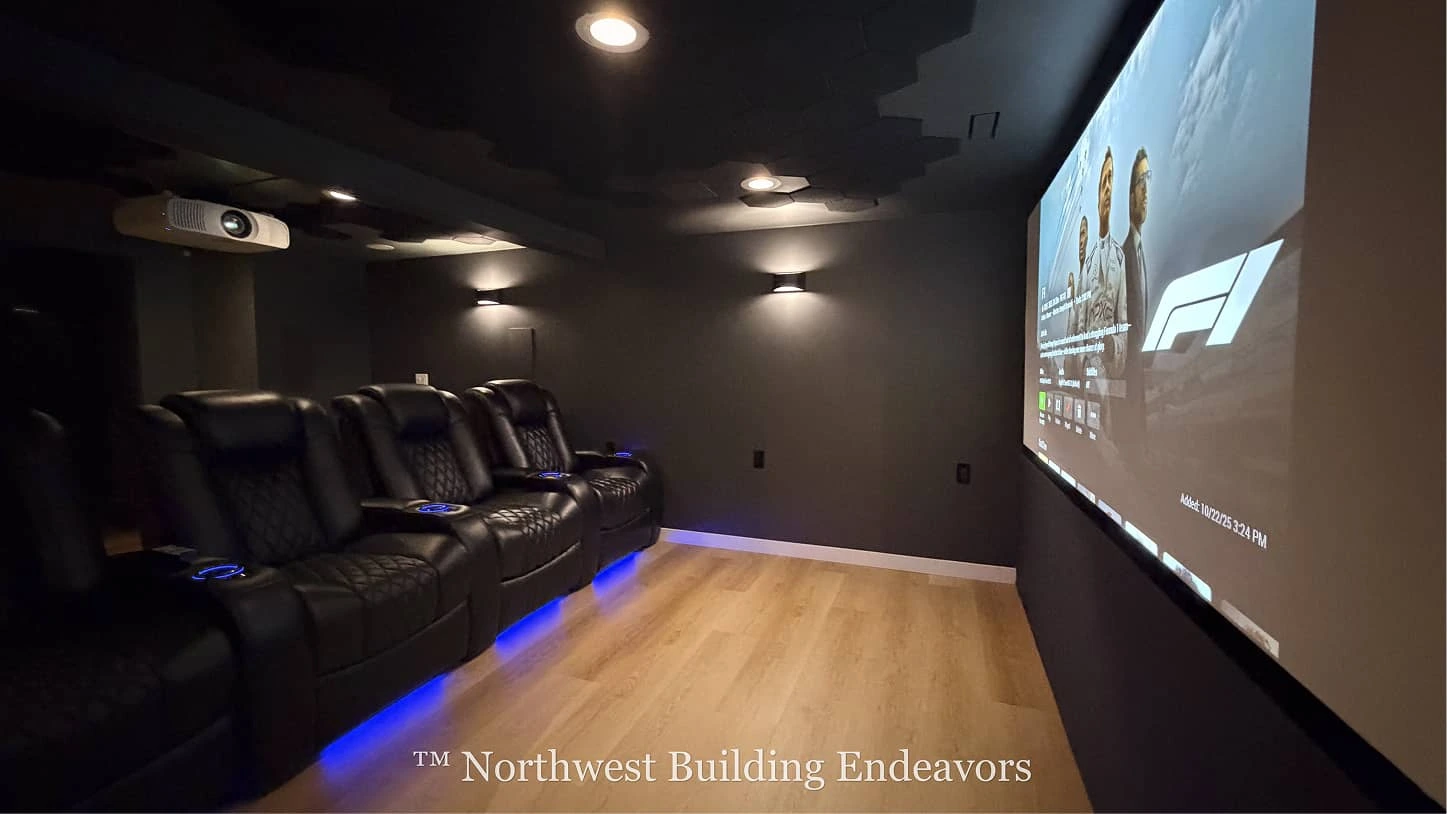 Modern home theater room with four black leather recliners illuminated by blue LED lights and a large projector screen showing a racing-related image.