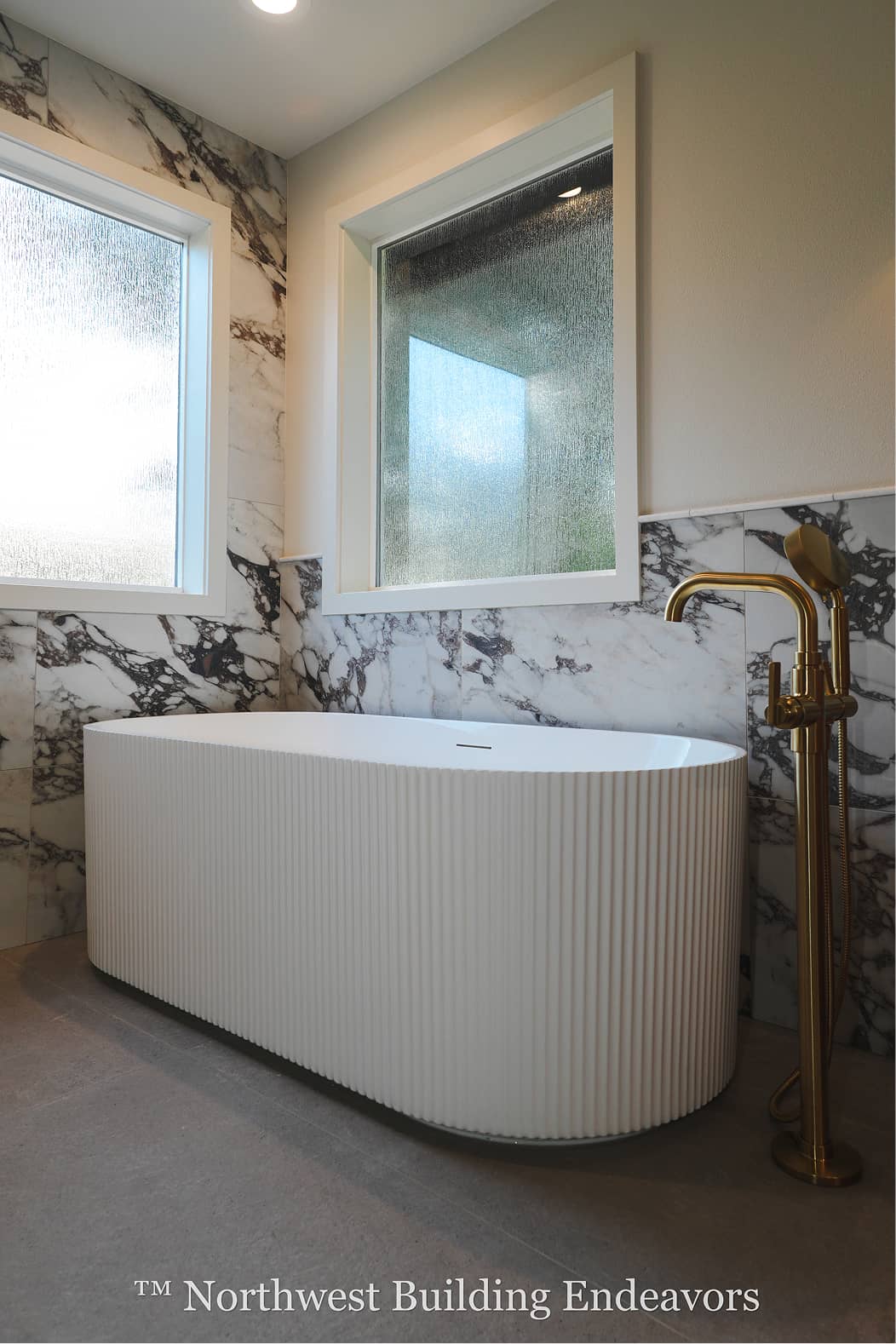 A small wooden guest house with large glass sliding doors and warm interior lighting, next to a larger house during twilight.