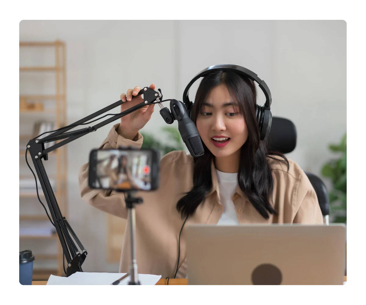 Content creator in a studio holding a tablet during a recorded product demo, promoting the Kommunicate Affiliate Program.