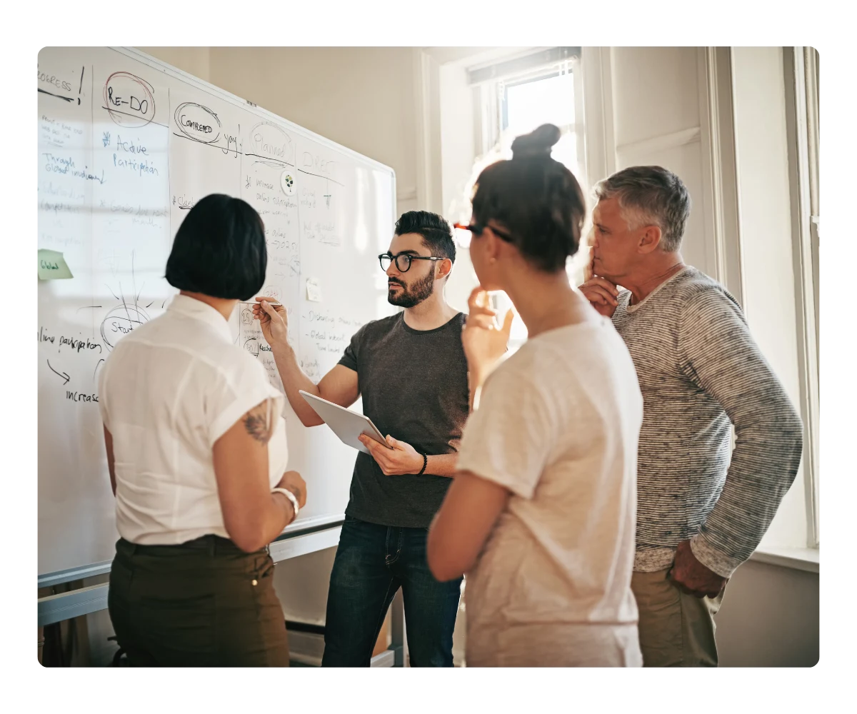 Agency team collaborating at a whiteboard, planning to recommend Kommunicate to clients via an affiliate link.