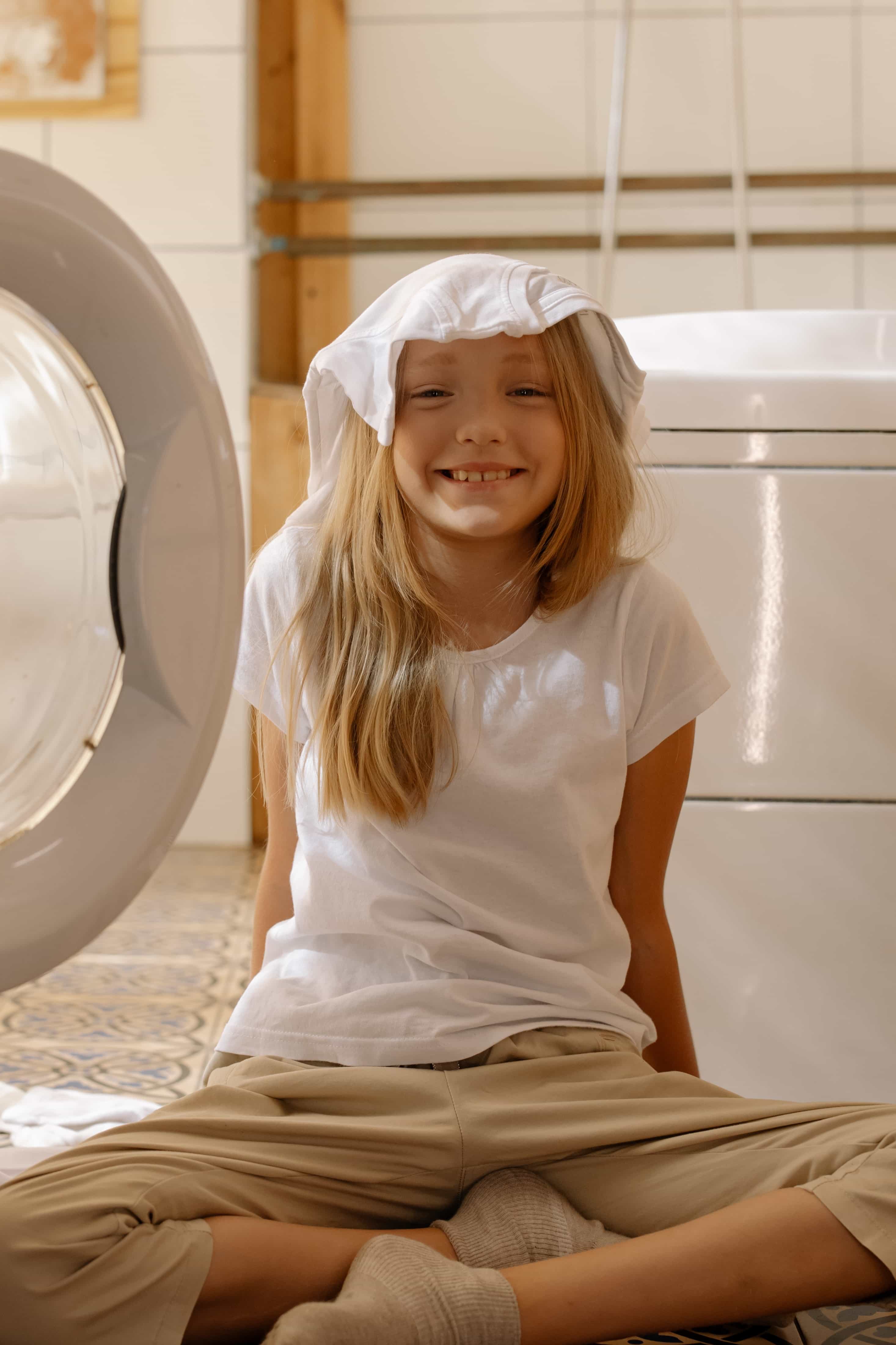 Girl sitting on floor next to dryer